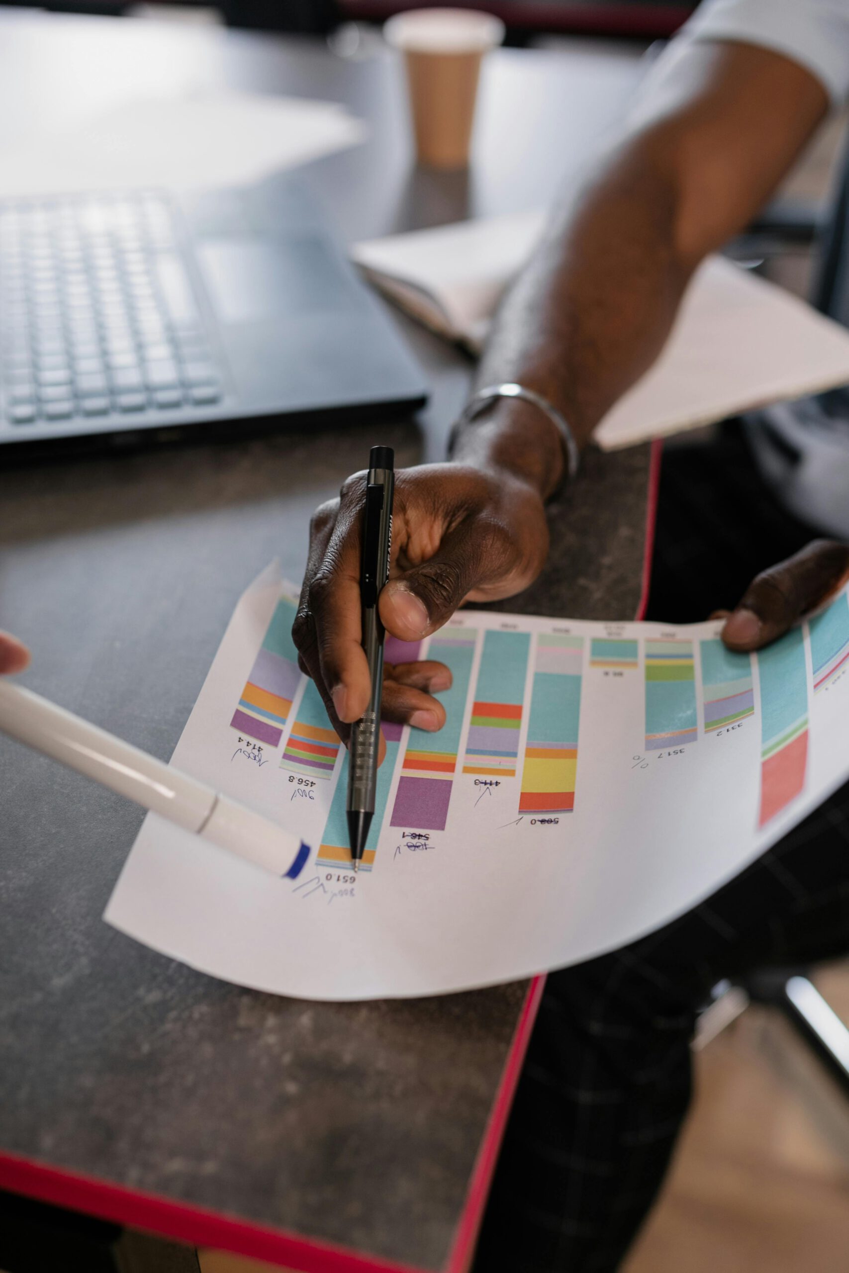 Close-up of hands analyzing colorful graphs at a business meeting, indicating strategic planning.